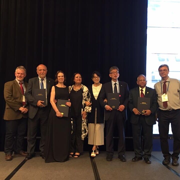 8 people in formal attire lined up holding the awards they received 