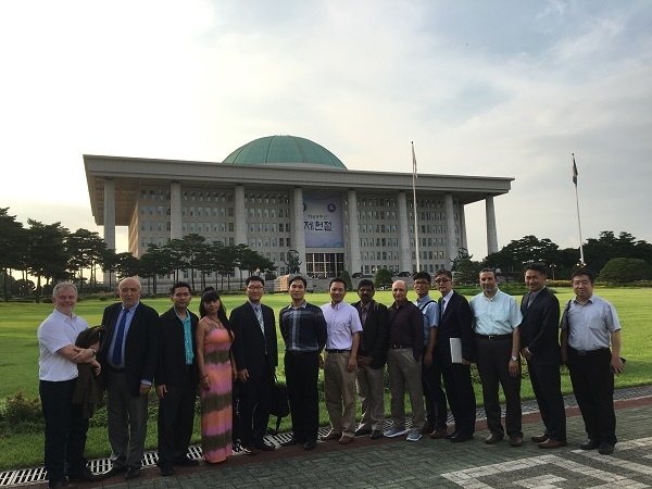 14 people lined up in front of a large building outside smiling