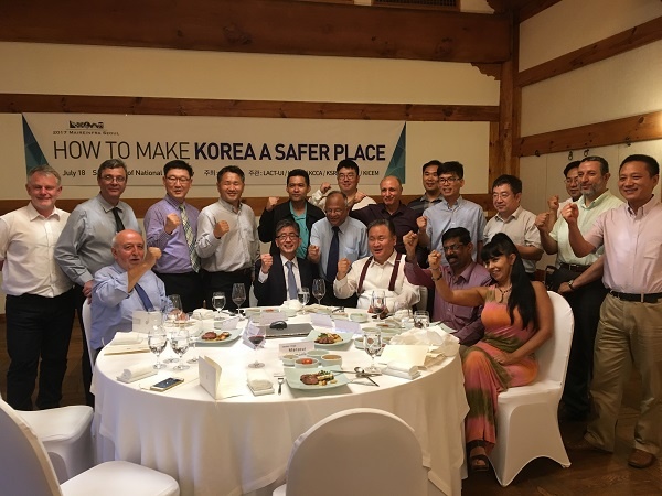 21 people gathered around a round dining table with their fists in the air smiling, they are wearing formal attire 