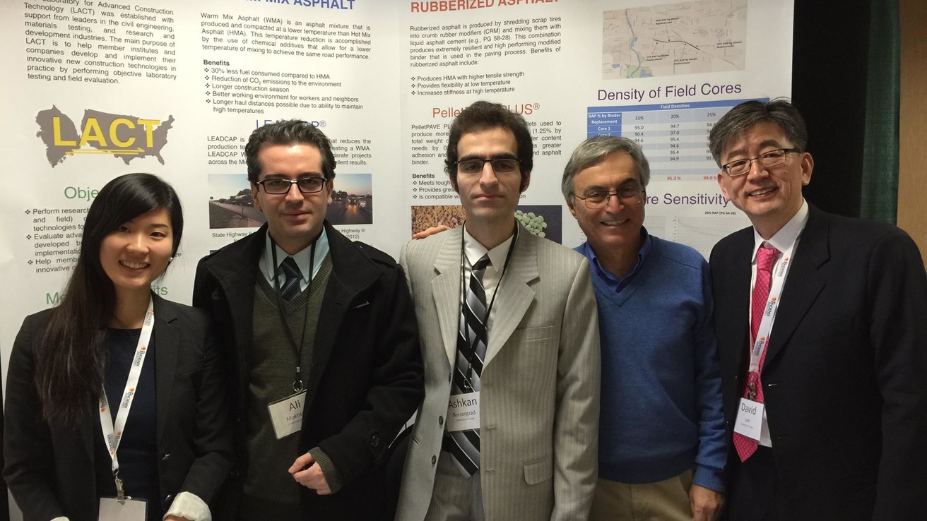 5 people standing in front of a large poster